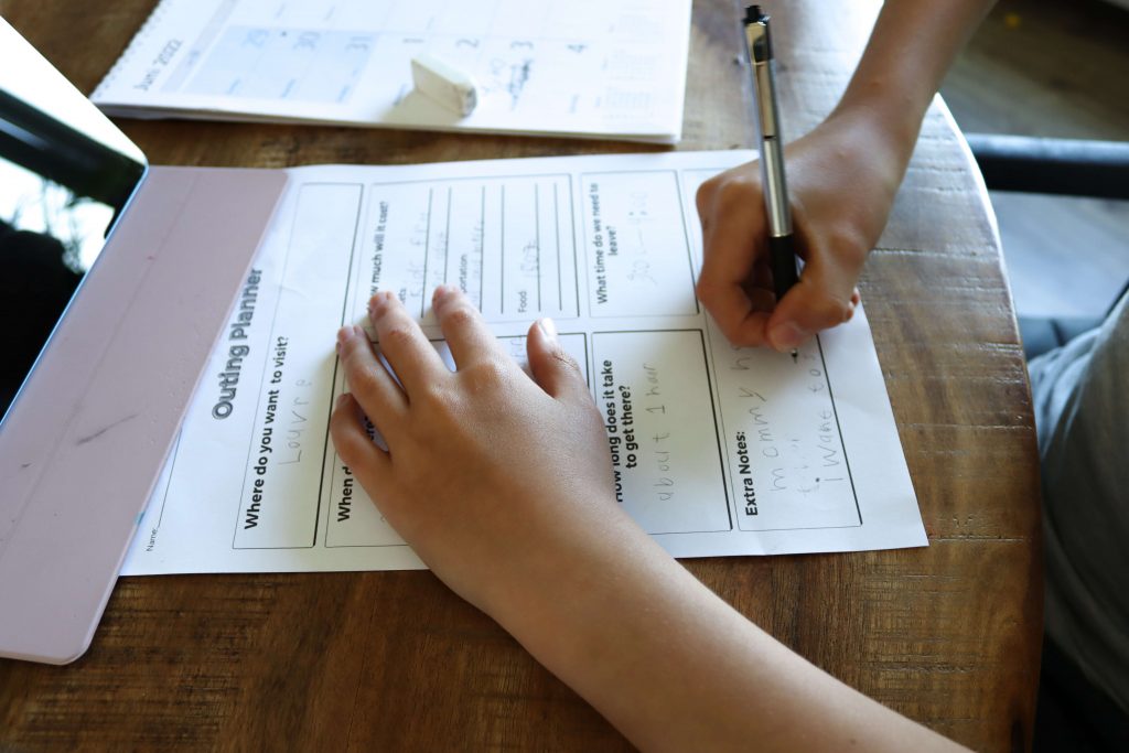Child filling out Montessori outing planner worksheet. In Montessori schools, elementary aged children are given the opportunity to organise, plan, and prepare for a trip outside of the classroom!